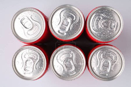 Energy drinks in wet cans on light grey background, top view