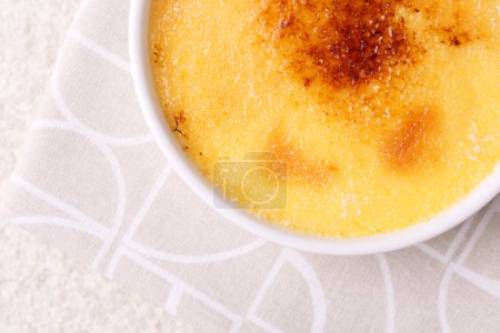 Foto de Deliciosa crema brulee en tazón en la mesa de textura ligera, vista superior. Espacio para texto - Imagen libre de derechos