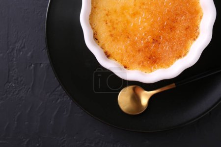 Foto de Deliciosa crema brulee en un tazón servido en una mesa de textura gris oscuro, vista superior - Imagen libre de derechos