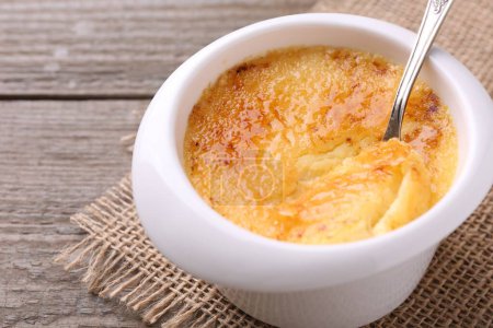 Photo for Delicious creme brulee in bowl served on wooden table, closeup - Royalty Free Image