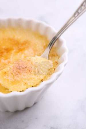 Foto de Comer deliciosa crema brulee en la mesa blanca, primer plano - Imagen libre de derechos