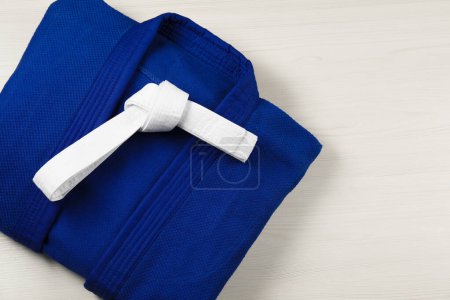 Photo for White karate belt and blue kimono on wooden background, top view. Space for text - Royalty Free Image