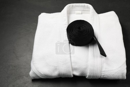 Cinturón de karate negro y kimono blanco sobre fondo gris