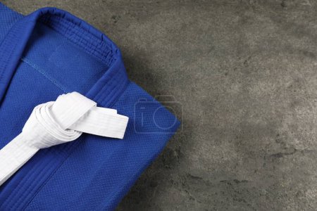 Photo for White karate belt and blue kimono on gray textured background, top view. Space for text - Royalty Free Image