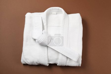 Cinturón de karate blanco y kimono sobre fondo marrón, vista superior