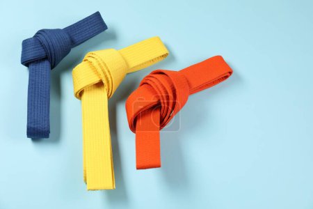 Photo for Colorful karate belts on light blue background, flat lay. Space for text - Royalty Free Image