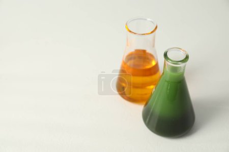 Photo for Glass flasks with different types of oil on white table, space for text - Royalty Free Image