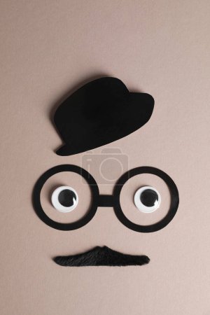 Téléchargez les photos : Visage d'homme en fausse moustache, chapeau en papier et lunettes sur fond gris, vue de dessus - en image libre de droit
