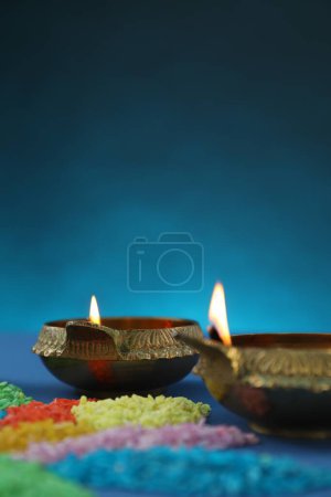 Téléchargez les photos : Fête de Diwali. Lampes Diya et rangoli coloré sur fond bleu, gros plan. Espace pour le texte - en image libre de droit