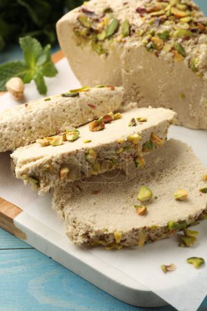 Pieces of tasty halva with pistachios on table, closeup