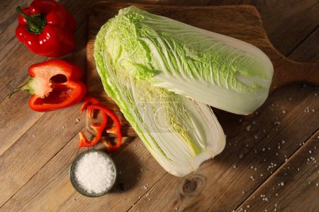 Fresh Chinese cabbages, bell peppers and salt on wooden table, flat lay