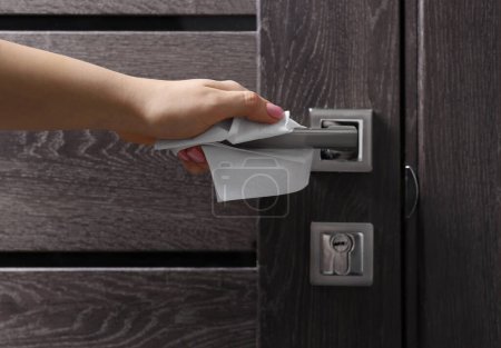 Woman wiping door handle with paper towel, closeup