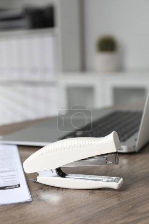 Stapler on wooden table indoors, closeup view