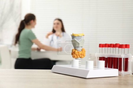 Photo for Endocrinologist examining patient at clinic, focus on model of thyroid gland and blood samples in test tubes - Royalty Free Image