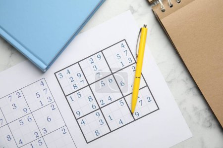 Foto de Sudoku, pluma, planificador y bloc de notas en la mesa de mármol blanco, la puesta plana - Imagen libre de derechos