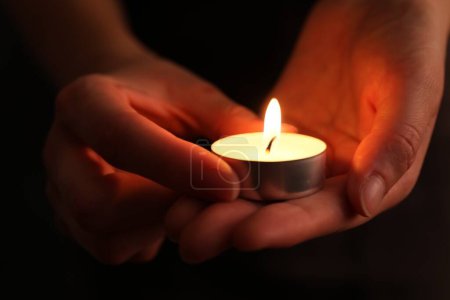 Frau mit brennender Kerze in der Dunkelheit, Nahaufnahme. Gedenktag