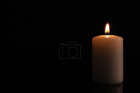 Burning candle on dark background, space for text. Memory day