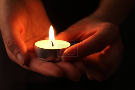 Frau mit brennender Kerze in der Dunkelheit, Nahaufnahme. Gedenktag
