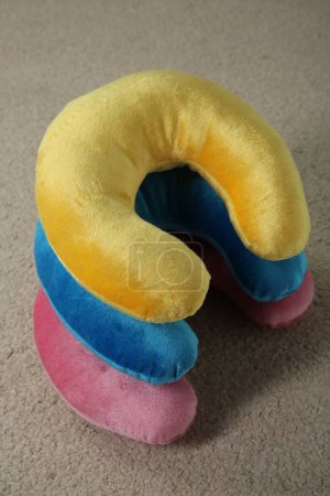 Many colorful travel pillows on beige rug