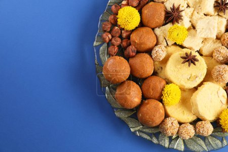Diwali-Feier. Leckere indische Süßigkeiten, Gewürze und Nüsse auf blauem Tisch, Draufsicht. Raum für Text