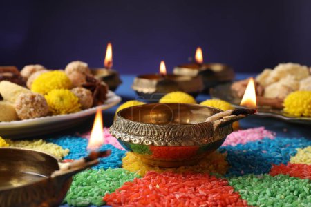 Téléchargez les photos : Fête de Diwali. Lampe Diya et rangoli coloré sur table sur fond violet, gros plan - en image libre de droit