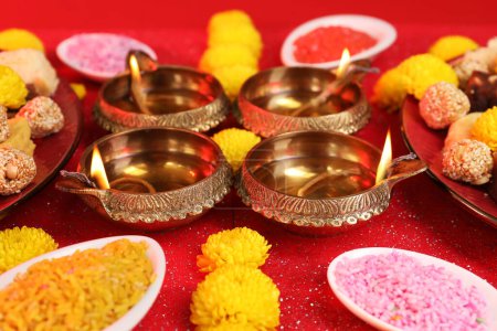 Diwali-Feier. Schöne Komposition mit Diya-Lampen und hellen Rangoli auf leuchtend rotem Tisch