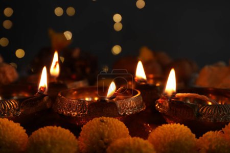 Téléchargez les photos : Fête de Diwali. Lampes Diya et fleurs de chrysanthème sur la table contre les lumières floues, gros plan - en image libre de droit
