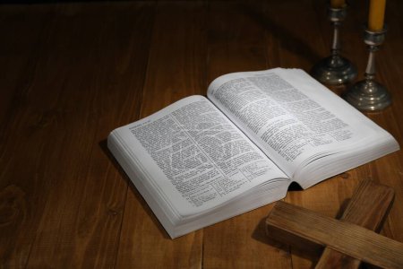 Bíblica, cruz y velas de iglesia sobre mesa de madera