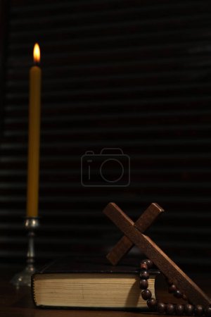 Photo for Church candle, Bible, cross and rosary beads on wooden table - Royalty Free Image