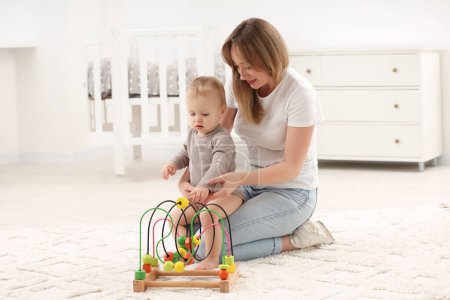 Kinderspielzeug. Mutter und ihr kleiner Sohn spielen mit Perlen-Labyrinth auf Teppich zu Hause