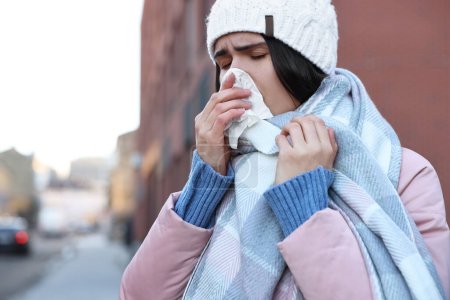 Photo for Woman with tissue blowing runny nose outdoors, space for text. Cold symptom - Royalty Free Image
