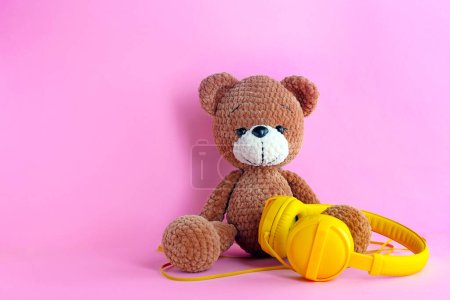 Babylieder. Spielzeugbär und gelbe Kopfhörer auf rosa Hintergrund, Platz für Text