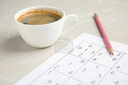 Foto de Sudoku, taza de café y lápiz en la mesa de mármol claro, primer plano - Imagen libre de derechos