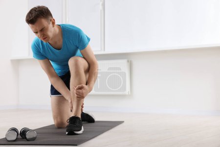 Photo for Man suffering from leg pain on mat indoors. Space for text - Royalty Free Image