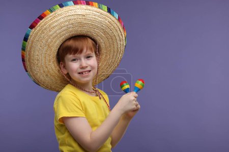 Lindo chico en sombrero mexicano con maracas sobre fondo violeta, espacio para texto