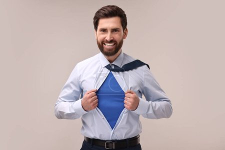 Foto de Feliz hombre de negocios con traje de superhéroe debajo del traje sobre fondo beige - Imagen libre de derechos