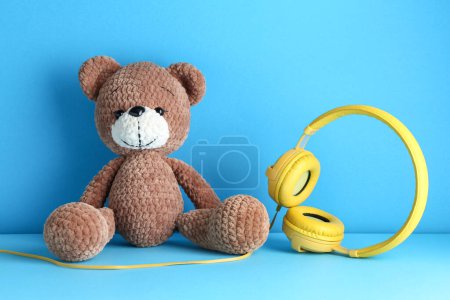 Babylieder. Spielzeugbär und gelbe Kopfhörer auf hellblauem Hintergrund
