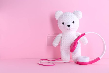 Babylieder. Spielzeugbär und Kopfhörer auf rosa Hintergrund, Platz für Text