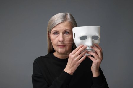 Photo for Multiple personality concept. Woman with mask on gray background - Royalty Free Image