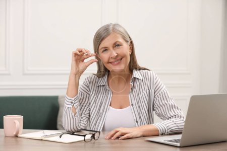 Menopause, hormone replacement therapy. Happy woman holding pill at wooden table indoors