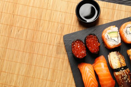 Téléchargez les photos : Délicieux rouleaux de sushi et sauce soja sur le tapis, à plat. Espace pour le texte - en image libre de droit