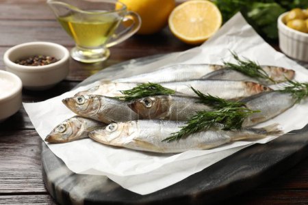 Photo for Fresh raw sprats, dill and other products on wooden table, closeup - Royalty Free Image