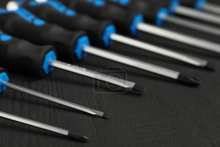 Set of screwdrivers on black wooden table, closeup