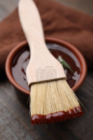 Marinade in bowl and basting brush on table, closeup