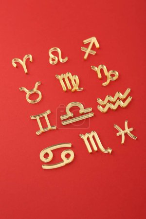 Shiny zodiac signs on red background, closeup