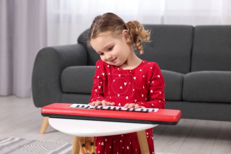 Little girl playing toy piano at home
