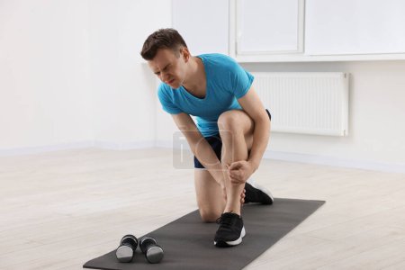 Photo for Man suffering from leg pain on mat indoors - Royalty Free Image