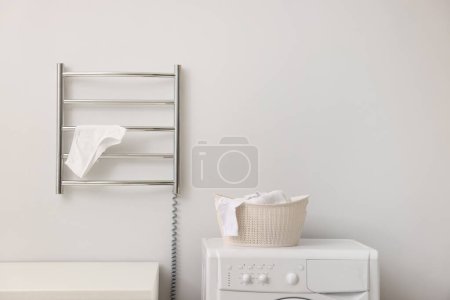 Beheizter Handtuchhalter mit Unterwäsche an weißer Wand im Badezimmer, Platz für Text