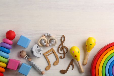 Téléchargez les photos : Concept de chanson de bébé. Des notes en bois, des maracas pour enfants et des jouets sur la table. Espace pour le texte - en image libre de droit