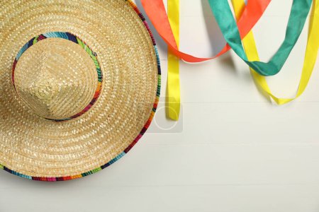Chapeau sombrero mexicain et rubans colorés sur fond bois blanc. Espace pour le texte